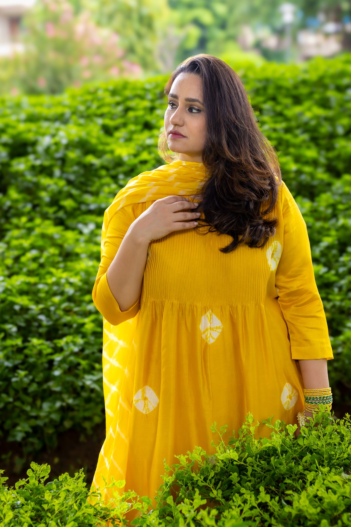 Close-up left view of model in yellow Bandhej kurta set.