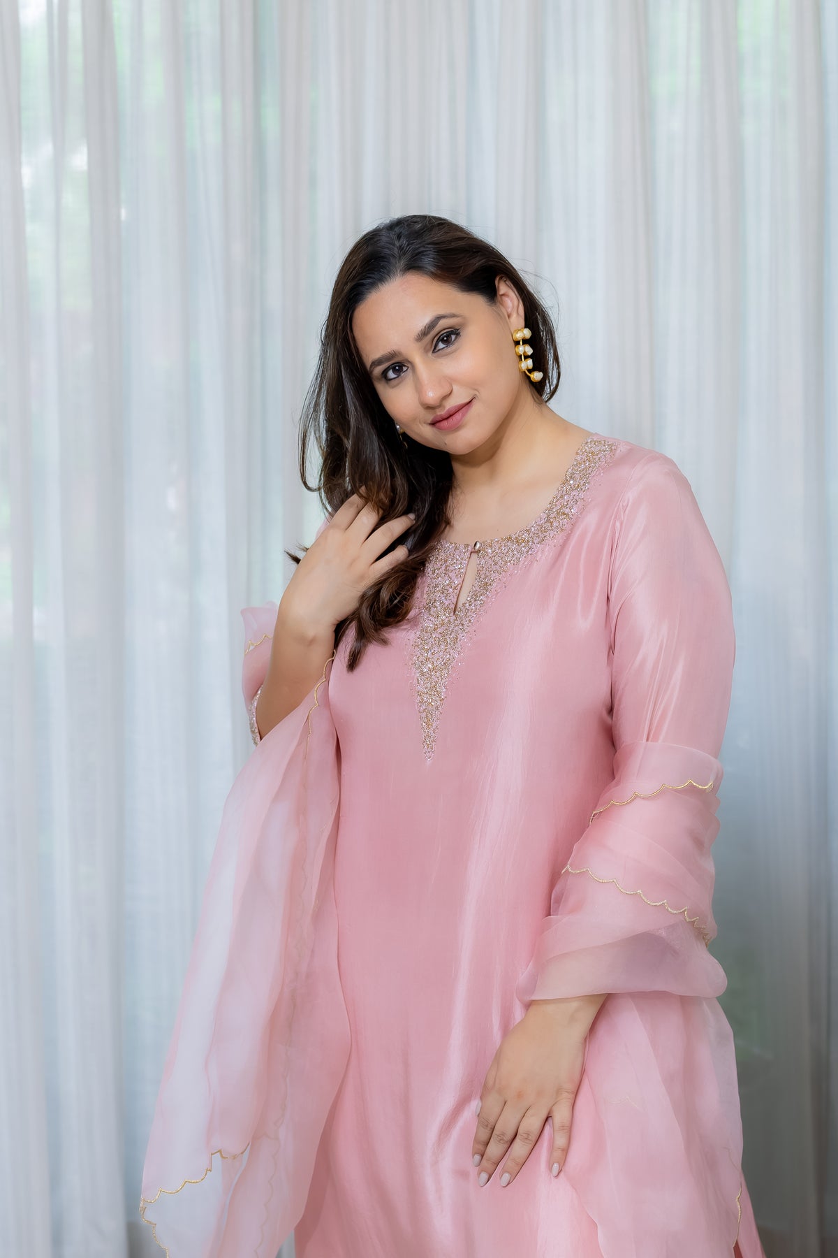 Woman wearing a pink traditional organza kurta set with gold embroidery 