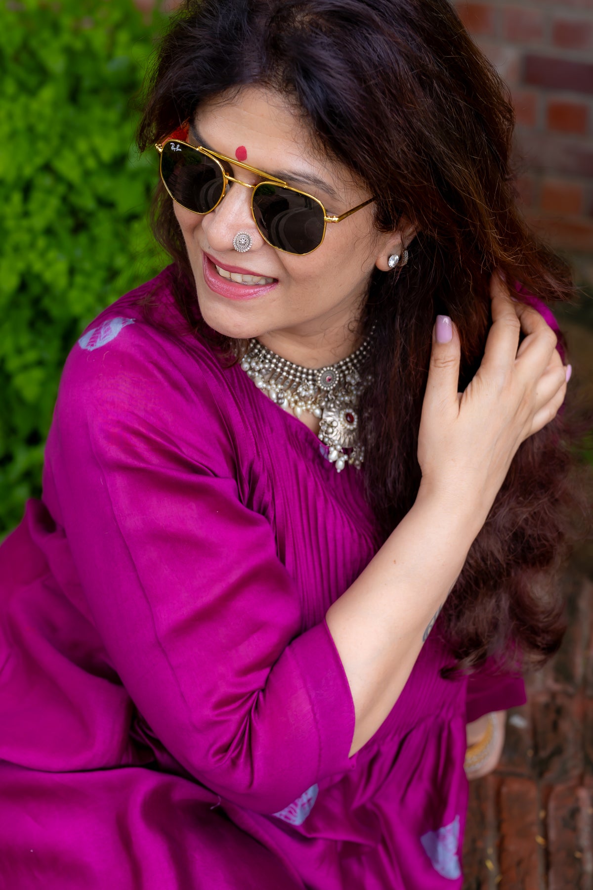 close up view of model sitting in preet bandhej magenta colored kurta set.