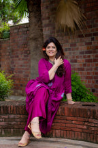 Front view of model sitting pose in preet bandhej magenta kurta set