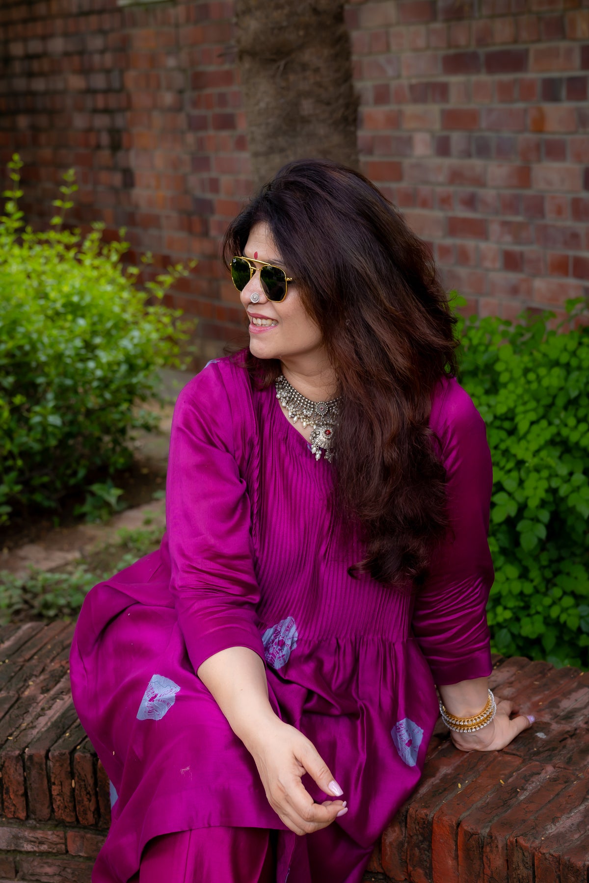 model sitting left view of preet bandhej magenta colored kurta set